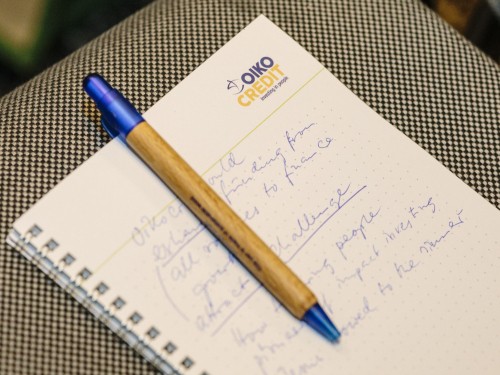 A pen and a notebook with Oikocredit's logo.