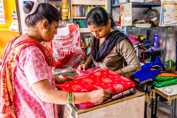 Two women examining fabric in a small shop