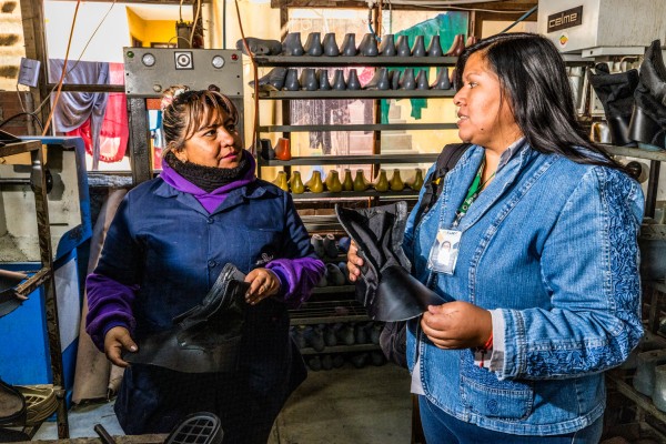 A microfinance client and a loan officer in a shoe factory.